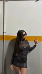 Minivestido negro traslúcido con brillos, cuello alto y mangas largas.