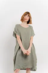 Vestido corto color verde oliva, confeccionado en lino, con corte recto y mangas cortas. Presenta bolsillos laterales y botones decorativos en los laterales.