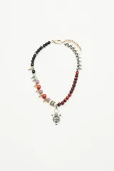 Gargantilla corta con cuentas de diferentes colores y texturas, separadas por piezas metálicas doradas y plateadas. Incluye dije central con forma de escudo plateado.