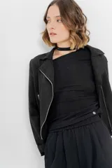 Chaqueta color beige de tela tipo gamuza con elastano, cuello solapa, manga larga con trabillas en hombro, bolsillos delanteros con cremallera metálica y cierre frontal con cremallera.