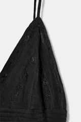 Vestido corto negro con tirantes finos y escote en V. Presenta bordados a tono en la parte superior.