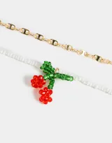Collar corto multicadena, con una cadena dorada de eslabones grandes y otra de mostacillas blancas, con dije de cerezas rojas y hojas verdes hechas de mostacillas.