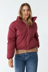Campera puffer verde oscuro de nylon, con cuello alto, cierre frontal con cremallera, bolsillos laterales y cintura ajustable con cordón.
