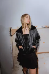 Campera bomber negra de cuero con cuello de piel sintética, forro interior y detalles de pasamanería en cuero marrón gastado.