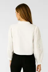 Blusa color crema de algodón con volados, corte holgado, escote en V y lazos para atar.