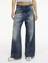 Pantalón de jean de tiro medio con pierna ancha, color azul con efecto desgastado y roturas en la parte delantera.