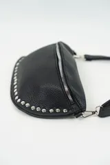 Riñonera negra de cuero sintético con correa ajustable y cierre superior con cremallera. Decorada con tachas plateadas en el borde inferior.