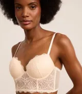 Soutien alargado color piel, confeccionado en encaje floral, con copa hueca y aro, tirantes ajustables y cierre trasero.