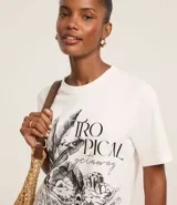 Remera blanca de algodón con cuello redondo y mangas cortas. Estampa frontal con lettering "Tropical Getaway" y dibujo del Parque Lage.