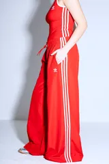 Pantalón Adidas Parachute negro de corte holgado con las tres rayas blancas a los costados.