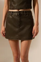Minifalda de cuero sintético color verde oscuro, de corte recto y con bolsillos delanteros.