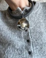 Collar corto con tira de cuero trenzado color gris y dije plateado con piedra blanca.