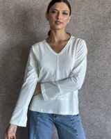 Remera blanca de manga larga con cuello en V y costuras a la vista.