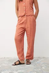 Pantalón de lino color ocre, de corte recto, con pinzas en la cintura y bolsillos laterales. Se combina con un chaleco haciendo juego.
