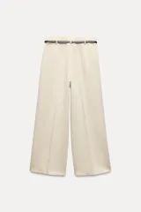 Pantalón culotte color crema, de tiro medio y pierna ancha. Incluye cinturón marrón con hebilla metálica.
