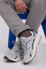 Zapatillas deportivas grises con detalles en azul marino. Confeccionadas en tejido de malla con forro de poliéster y suela de goma.