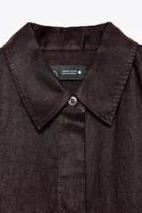 Camisa de lino color verde oliva, con cuello solapa, manga larga con puños y cierre frontal con botones.