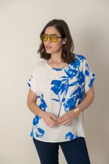 Blusa italiana de calce holgado, con cuello redondo y manga corta. Presenta un estampado de flores azules sobre fondo blanco.