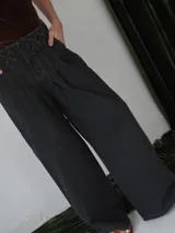 Pantalón vaquero de corte ancho, color crudo, con cintura alta y detalle de costuras cruzadas en la parte superior.
