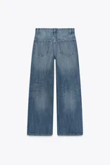 Jeans de tiro alto con pierna ancha y largo completo. Confeccionados en tejido rígido con cinco bolsillos, cintura con trabillas, detalle de costuras torcidas y cierre con cremallera y botón metálico.