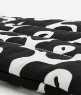 Funda para notebook con diseño tipo cartera, confeccionada en algodón con estampado floral bicolor en blanco y negro. Tiene cierre de cremallera y asa mediana.