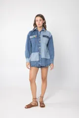 Camisa de jean con diseño patchwork en tonos azul y celeste, con cuello clásico, cierre frontal con botones y mangas largas.