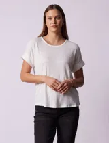Remera blanca texturada con cuello redondo y mangas cortas con dobladillo. Detalle de botones en la espalda.