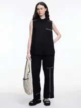 Pantalón negro de lino con elástico en la cintura y calce relajado. Incluye bolsillos laterales y un bolsillo invertido. Detalles de bordado tipo pespunte en color gris recorren la pierna y el bajo.