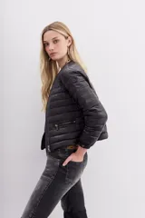 Campera corta negra de nylon rellena con pluma, corte holgado, cuello redondo y bolsillos con cierre.