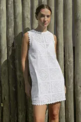 Vestido corto blanco con estampado de flores y diseño geométrico, sin mangas y con terminaciones onduladas en cuello y ruedo.