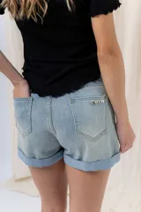 Short de jean azul claro con ruedo doblado fijo, tiro medio, calce cómodo, bolsillos delanteros y traseros, y cierre frontal con botón y cierre.