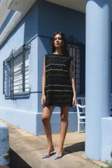 Minivestido negro tejido con lurex, escote redondo y falda con volados. Presenta líneas horizontales de colores azul, amarillo, verde y fucsia.