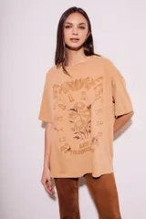 Remera color arena con estampa frontal de flores y texto "Les Tourness Bisou". Corte oversize.