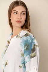 Camisa de lino blanca con estampado de flores azules y verdes, de corte holgado y manga corta.