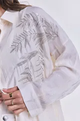 Camisa color crudo con bordados de lentejuelas plateadas en forma de hojas.