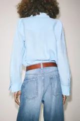 Camisa de lino color verde oliva, con cuello solapa, manga larga con puños y cierre frontal con botones.