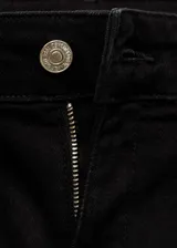 Pantalón de jean negro con tiro medio, corte acampanado y bajo deshilachado. Presenta cuatro bolsillos y cierre de cremallera con botón.