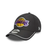 Gorra New Era gris oscuro con el logo de Los Angeles Lakers bordado en el frente. Tiene visera curva con borde blanco, corona estructurada y cierre ajustable en la parte posterior.