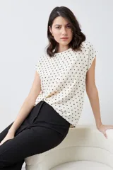 Blusa color crudo con estampado de puntos negros, de corte recto y manga corta.