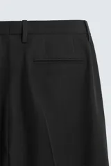 Pantalón de vestir azul marino, de corte slim fit, con bolsillos laterales y traseros. Se ajusta a la cintura con cinturón de cuero marrón.