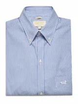 Camisa de manga larga a rayas verticales azules y blancas, confeccionada en popelina 100% algodón con tratamiento easy iron. Tiene cuello americano con botón, bolsillo en el pecho con logo bordado y calce regular.