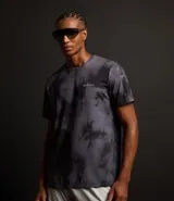 Remera deportiva negra con estampado manchado en gris y lettering en el pecho. Confeccionada en tejido dry de poliéster y elastano, con cuello redondo y mangas cortas.