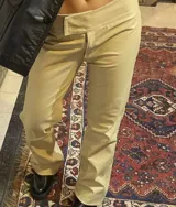 Pantalón de cuero color beige, tiro medio-bajo, con abertura lateral y cierre con clip.