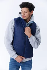 Chaleco acolchado azul marino con cierre frontal y cuello alto. Reversible, con interior en tono celeste. Sin mangas.