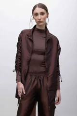 Pantalón de tafeta tornasolada color borgoña, de corte recto y tiro alto, con cintura elastizada, bolsillos frontales con cierre y cordones ajustables en las pantorrillas para fruncir el bajo.