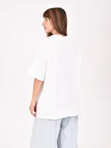 Remera blanca de corte holgado con cuello en V y estampado frontal con la frase 'Los Angeles' y el número '97' en color bordó.