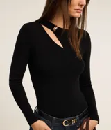 Blusa negra de punto acanalado, con mangas largas, cuello redondo con detalle metálico dorado y abertura asimétrica en el hombro.