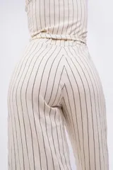 Mono largo color beige con rayas verticales negras, breteles finos, escote en V y lazo en la cintura.