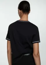 Camiseta negra de algodón con cuello redondo y ribetes blancos en cuello y mangas. Corte recto y manga corta.