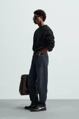 Jersey negro de corte boxy fit, tejido en hilatura con mezcla de algodón y 13% de cashmere. Tiene cuello redondo, manga larga y acabados en rib.